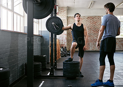 Buy stock photo Shot of two young men talking together after working out with weights in the gym
