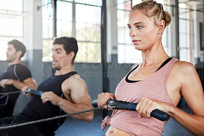 Buy stock photo Shot of a group of people working out on rowing machines in a gym