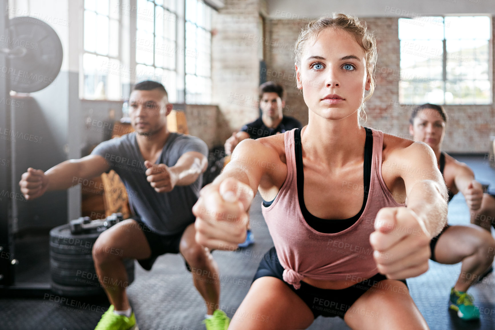 Buy stock photo Shot of a group of people doing squats in a gym