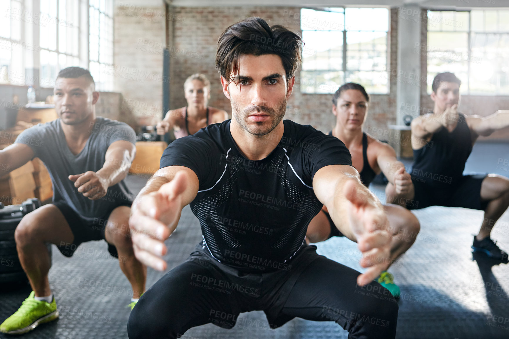 Buy stock photo Shot of a group of people doing squats in a gym