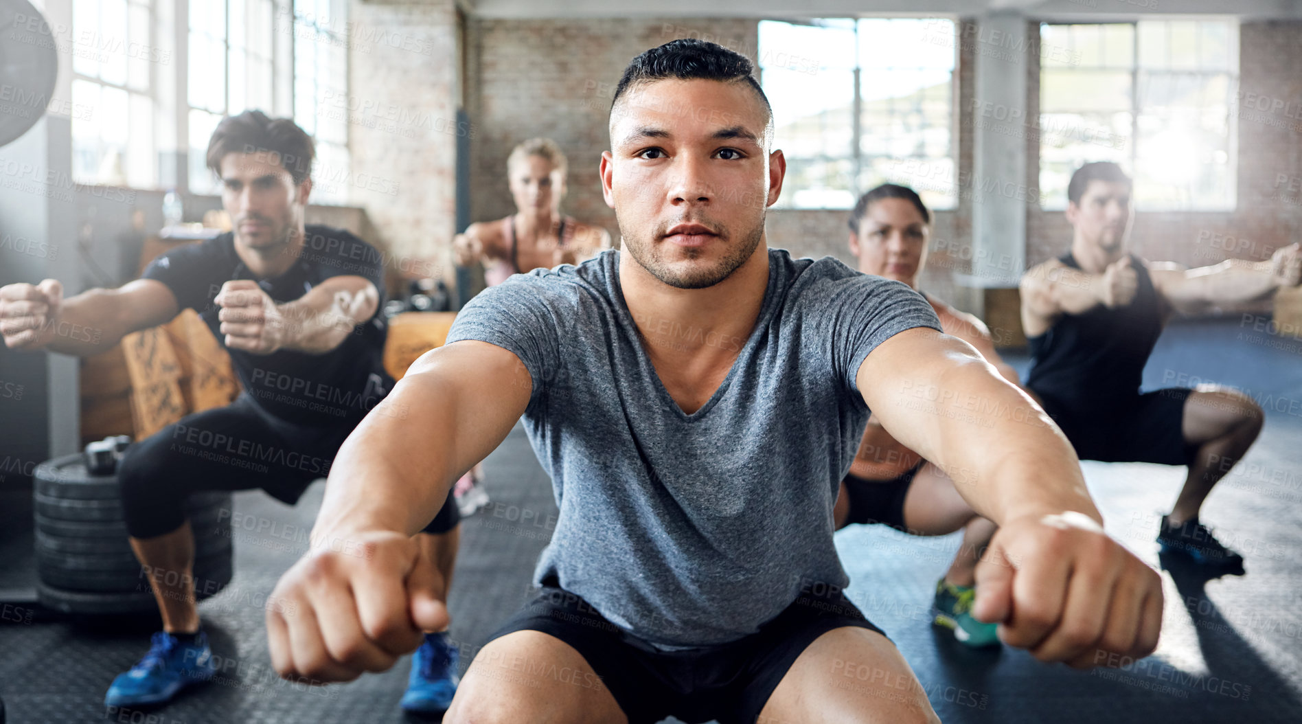 Buy stock photo Shot of a group of people doing squats in a gym