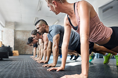 Buy stock photo Shot of a group of people doing push ups in a gym