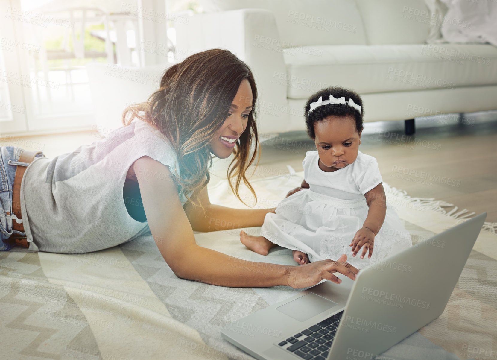 Buy stock photo Shot of a mother using a laptop with and her baby daughter at home