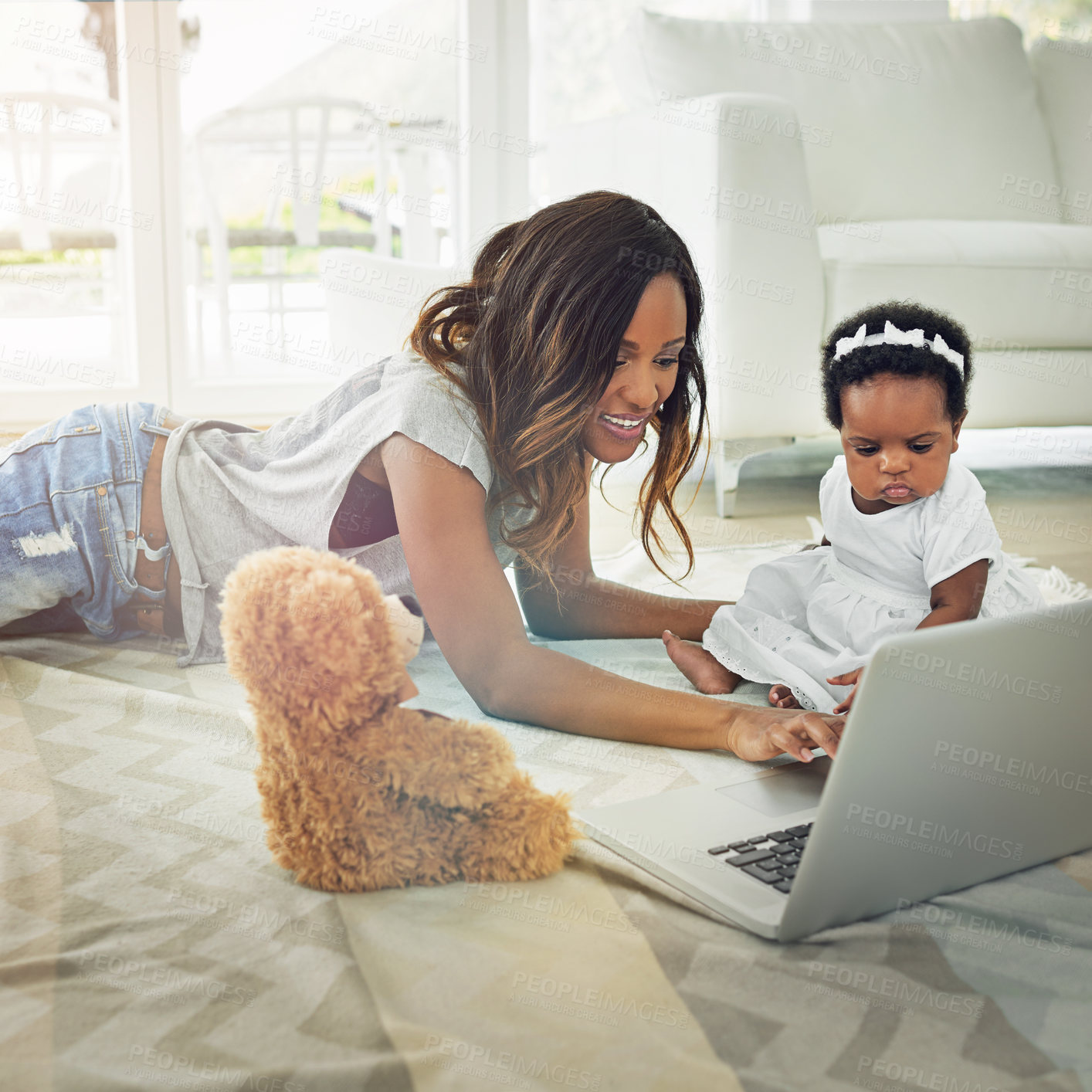 Buy stock photo Shot of a mother using a laptop with and her baby daughter at home