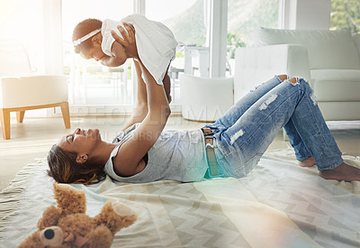 Buy stock photo Shot of a mother holding up her baby daughter at home