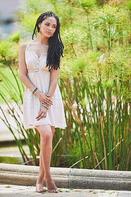 Buy stock photo Shot of a femininely dressed young woman posing in natural surroundings