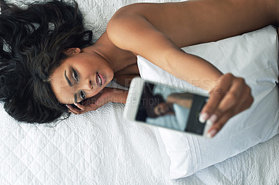 Buy stock photo Shot of a beautiful young woman taking a selfie while relaxing in her bedroom