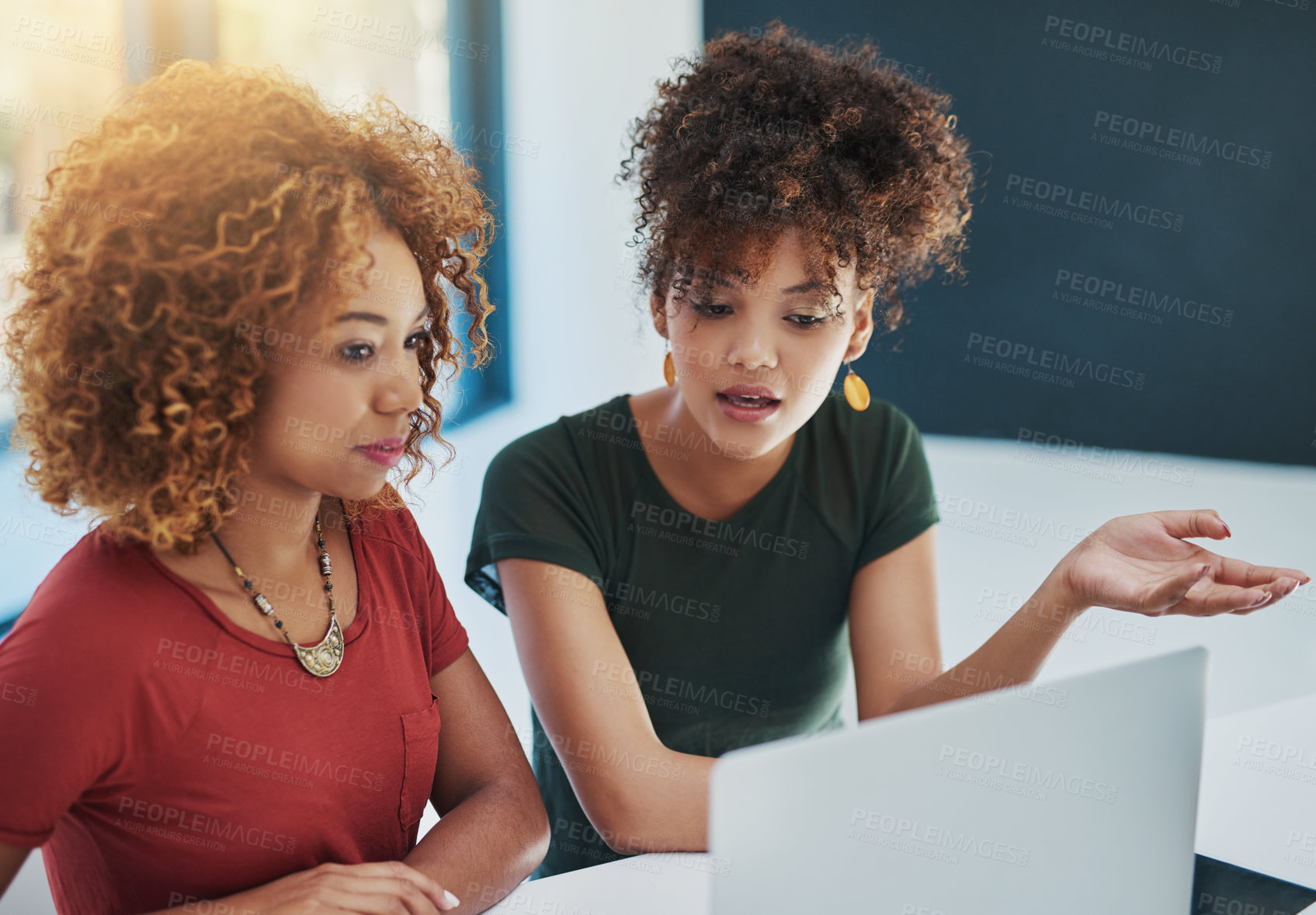 Buy stock photo Shot of two young designers working on a laptop together