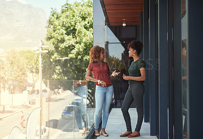 Buy stock photo Shot of two businesswomen chatting outside on a balcony