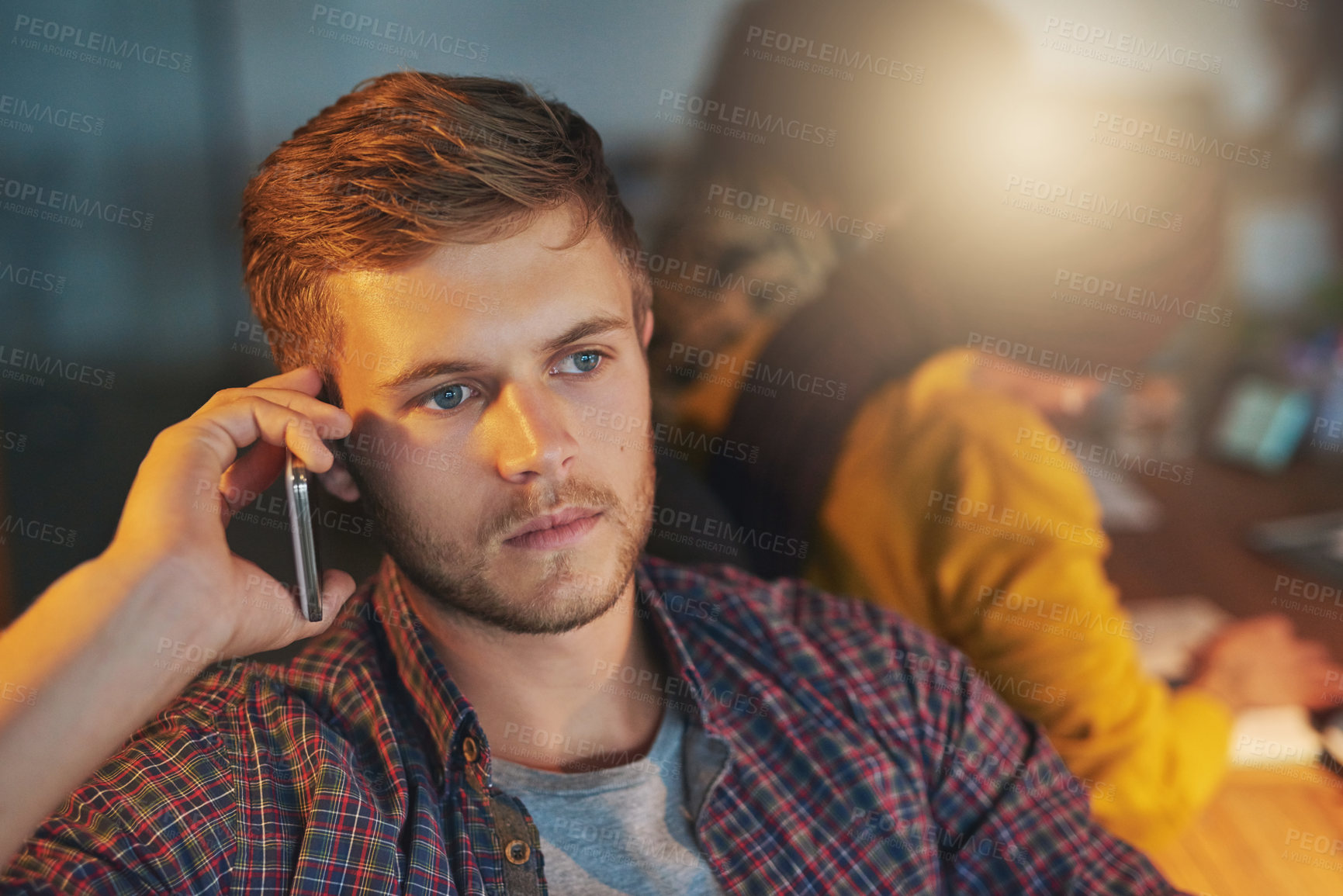 Buy stock photo Cropped shot of a young man using his cellphone while working late in the office