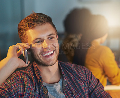 Buy stock photo Cropped shot of a young man using his cellphone while working late in the office