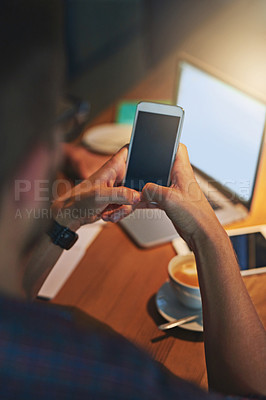 Buy stock photo Rearview shot of a young man using his cellphone while working late in the office
