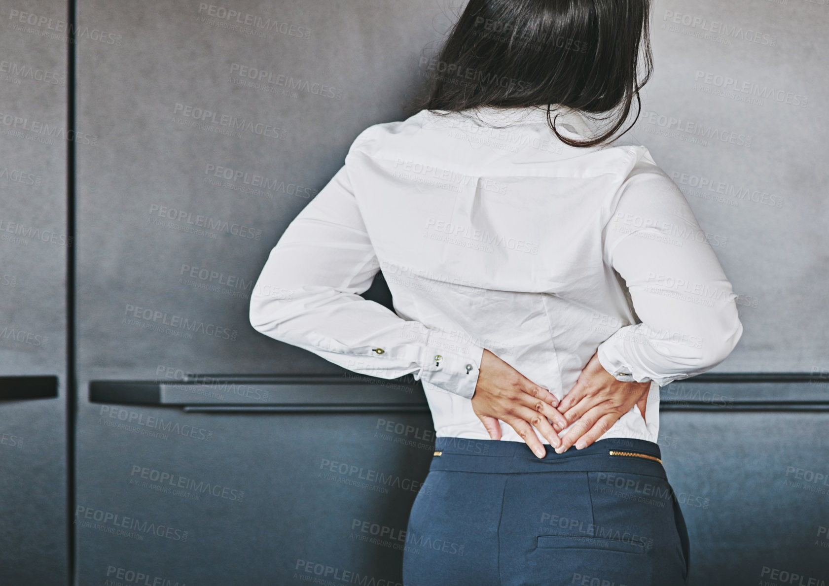 Buy stock photo Cropped shot of a businesswoman holding her lower back in discomfort