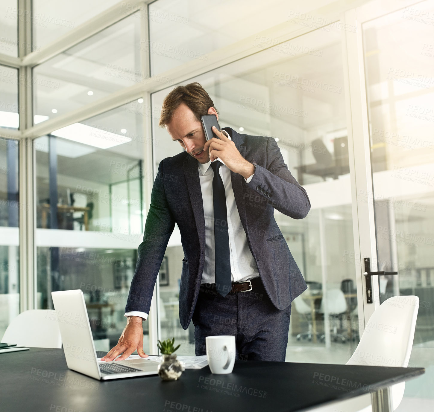 Buy stock photo Shot of a businessman talking on his cellphone while using his laptop