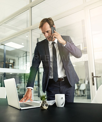 Buy stock photo Shot of a businessman talking on his cellphone while using his laptop