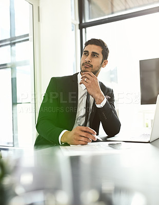 Buy stock photo Shot of a businessman looking thoughtful while sitting at his desk