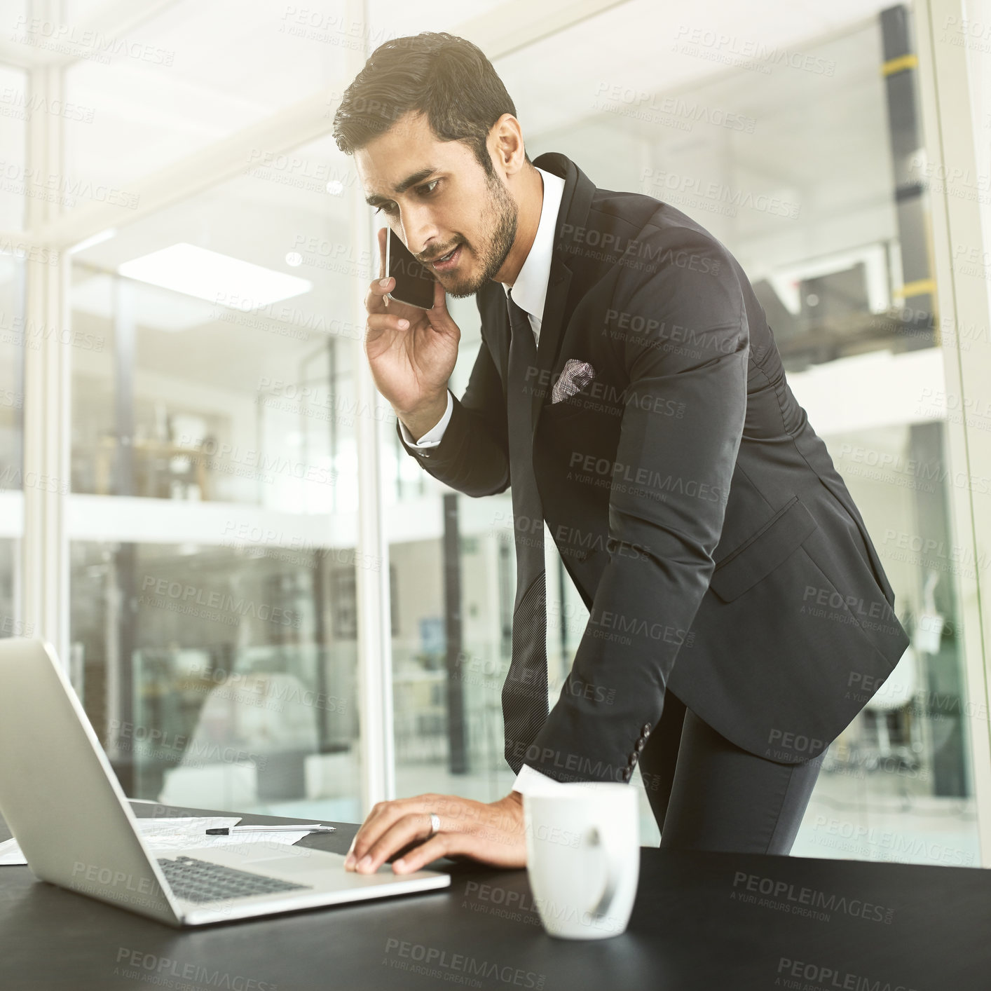 Buy stock photo Shot of a businessman talking on his cellphone while using his laptop