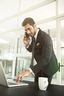 Buy stock photo Shot of a businessman talking on his cellphone while using his laptop