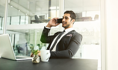 Buy stock photo Shot of a businessman talking on his cellphone while looking at his laptop