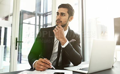 Buy stock photo Shot of a businessman looking thoughtful while using his laptop