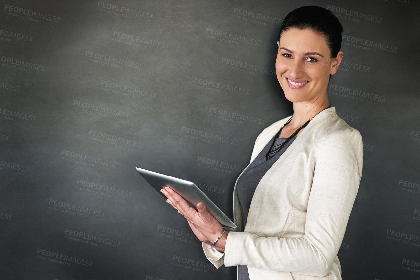 Buy stock photo Studio portrait of a businesswoman standing with a tablet against a grey background