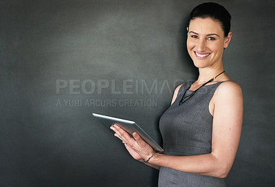 Buy stock photo Studio portrait of a businesswoman standing with a tablet against a grey background