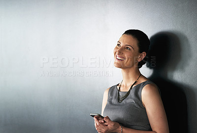 Buy stock photo Studio shot of a businesswoman using her cellphone against a grey background