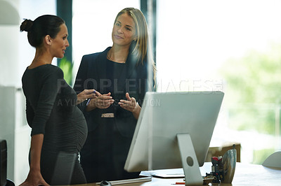 Buy stock photo Shot of a pregnant businesswoman and a colleague talking together in an office