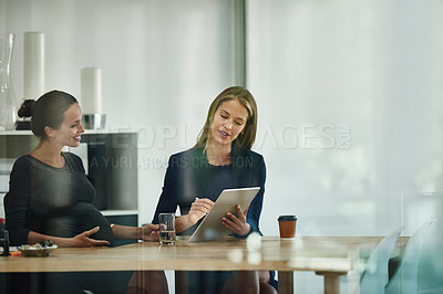 Buy stock photo Shot of a pregnant businesswoman and a colleague using a digital tablet together in an office