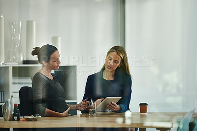 Buy stock photo Shot of a pregnant businesswoman and a colleague using a digital tablet together in an office