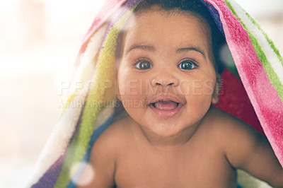 Buy stock photo Shot of an adorable baby girl covered in a colorful blanket at home