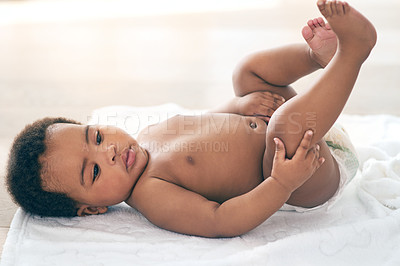 Buy stock photo Calm, cute and baby on a bed with a diaper, relax and curious while looking at feet at home. Black child, infant and adorable boy on a changing table, comfortable and relaxing alone in a nursery