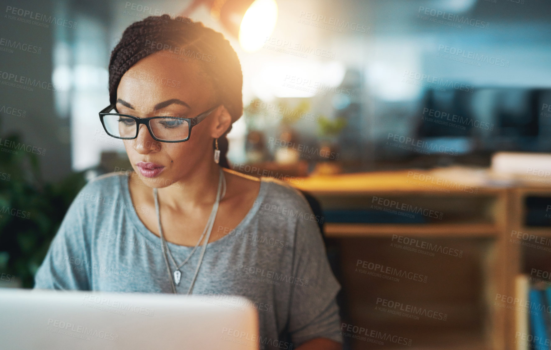 Buy stock photo Cropped shot of a young woman using her laptop while working late in her office