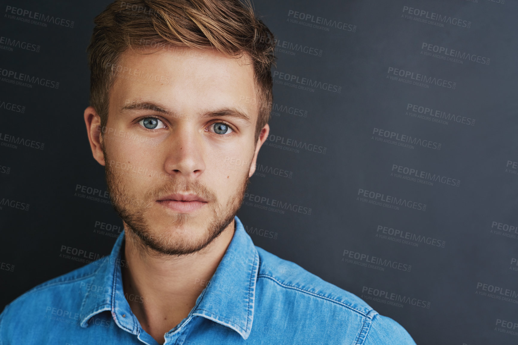 Buy stock photo Studio shot of a young man standing against a dark background