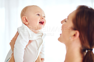 Buy stock photo Loving, caring and smiling mother carrying her baby at home bonding. Female embracing motherhood holding her baby in the air enjoying a sweet moment of love, care and happiness in the joy of life.