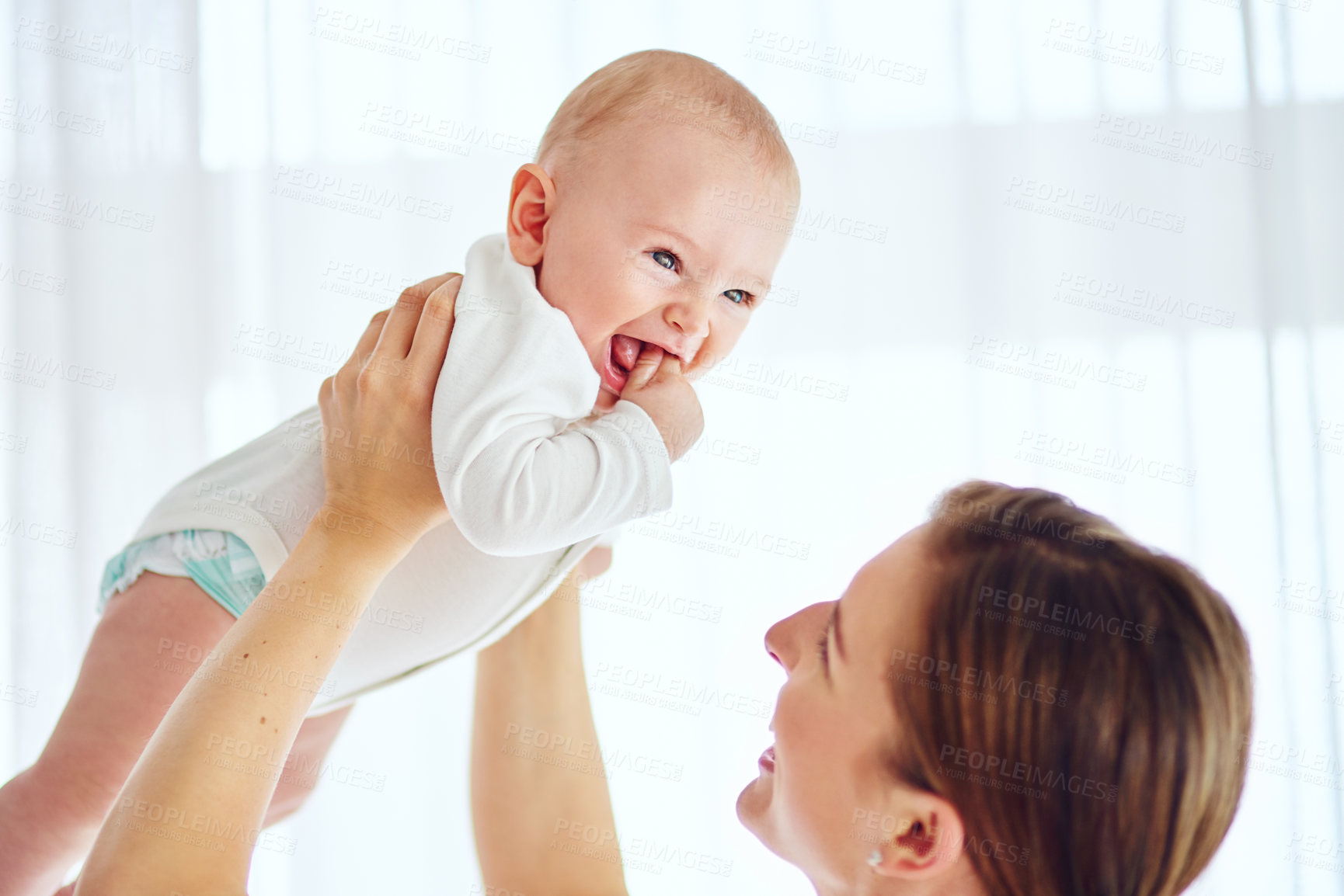 Buy stock photo Shot of a loving mother carrying her baby boy at home