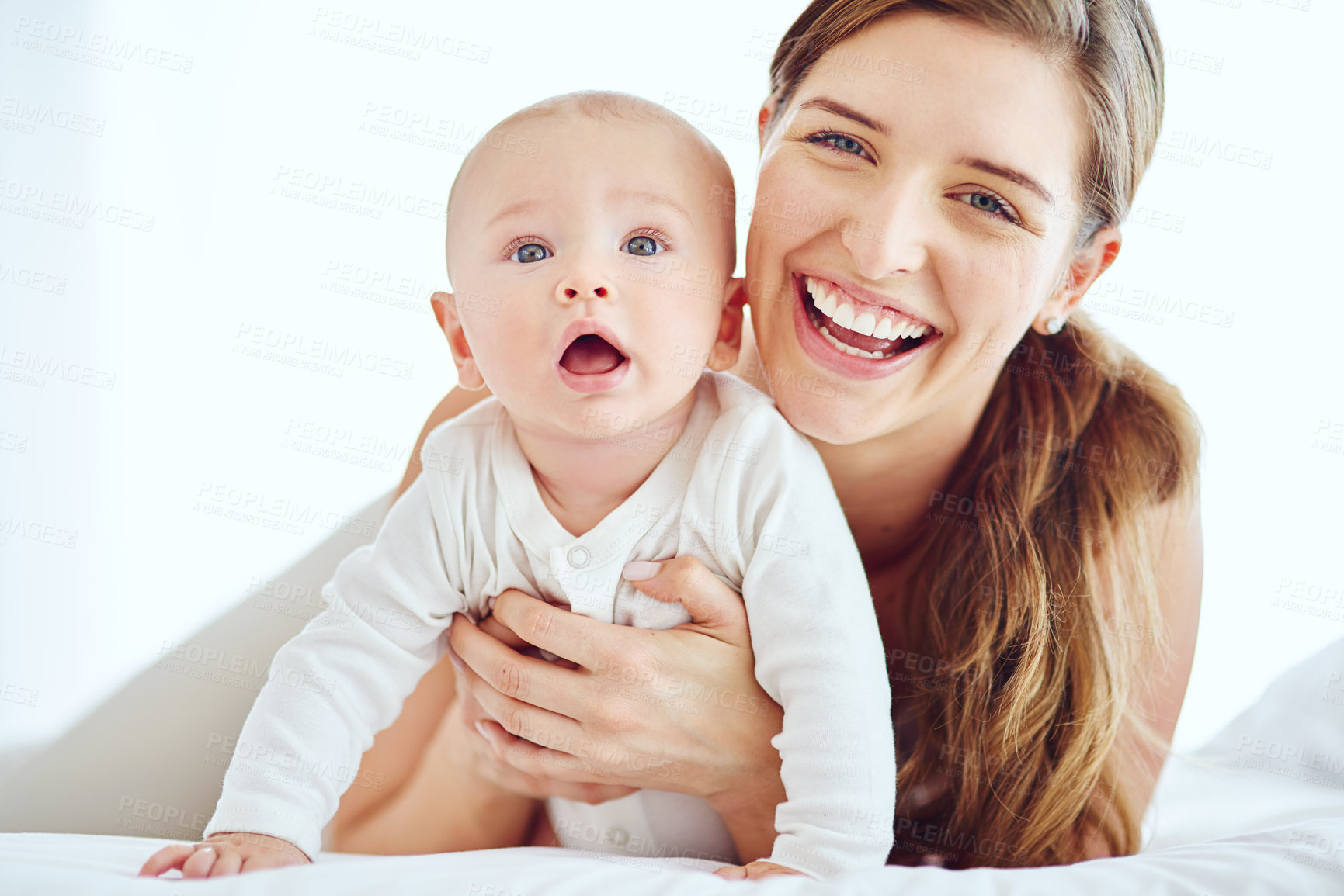 Buy stock photo Family, baby and bonding while smiling and lying on a bed together at home. Portrait of a happy, loving and caring mother holding her adorable infant son, laughing and feeling cheerful while cuddling