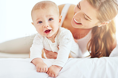 Buy stock photo Mother and cute, newborn baby boy bonding together as a family in the bedroom at home. Happy, smiling and carefree mom and son showing love and affection while relaxing on a bed in the morning
