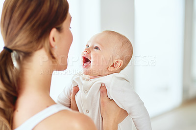 Buy stock photo Mother playing and bonding with cute baby boy and having fun indoors at home together. Loving mom holding her beautiful, playful and free child in the air. Woman enjoying spending time with her kid