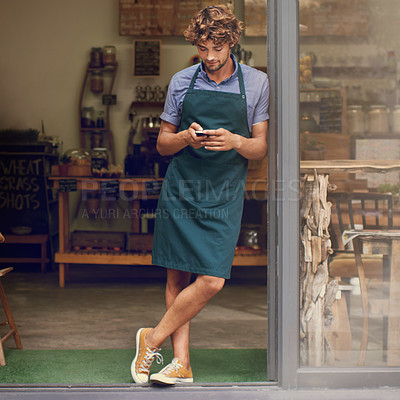Buy stock photo Coffee shop, typing and phone of a man as a small business owner at front door. Entrepreneur person as barista, manager or waiter in restaurant with mobile app for service, marketing or communication