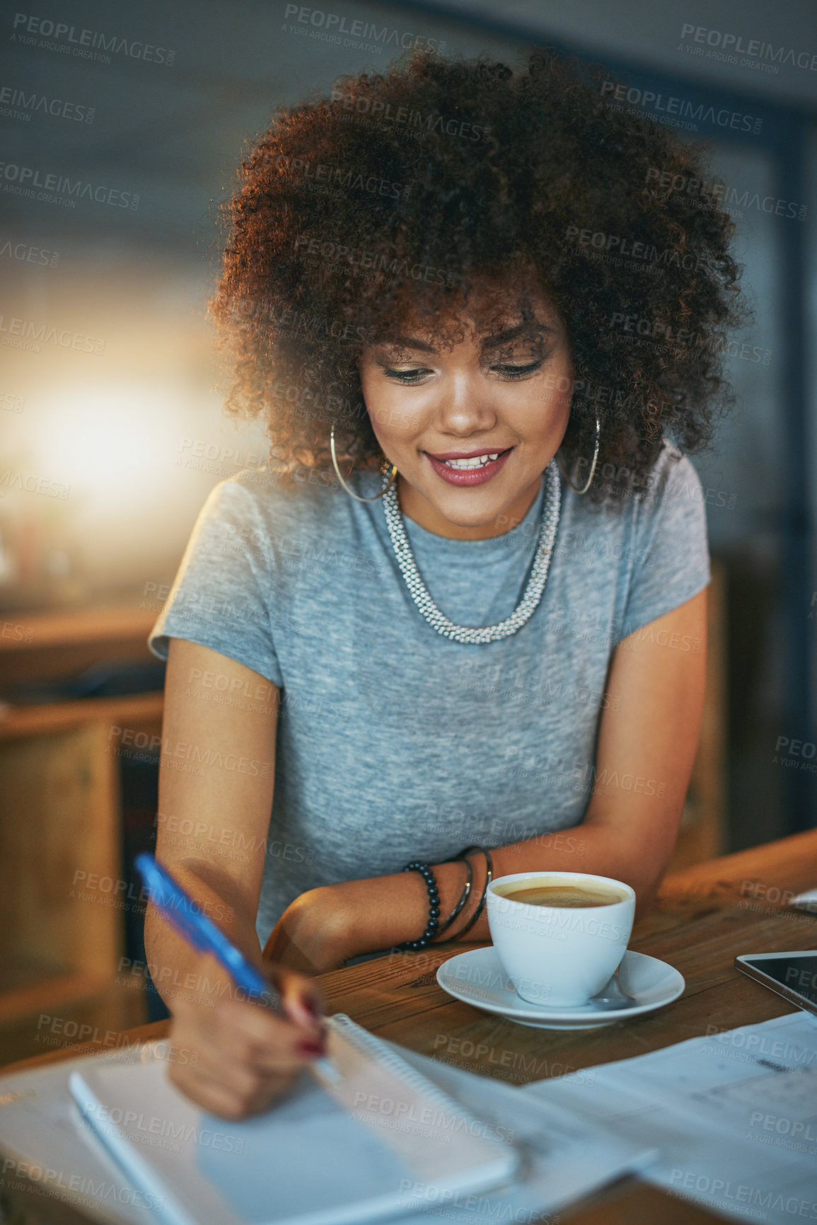 Buy stock photo Coffee, writing and black woman in office at night, working at desk for administration deadline. Afro, notebook and smile of happy design person in creative workplace for evening report or research