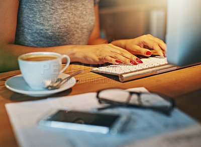 Buy stock photo Cropped shot of a woman working on a computer with coffee, a phone and paperwork in the foreground