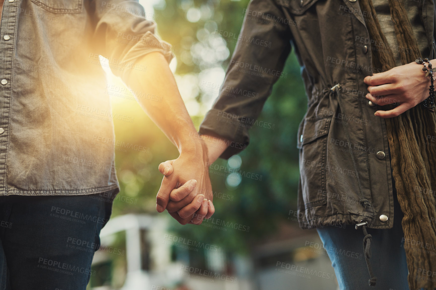 Buy stock photo Love, holding hands and couple in city for travel, journey and bonding outdoor with fun, freedom or adventure at sunset. Lens flare, trust and people outside for urban shopping, experience or date