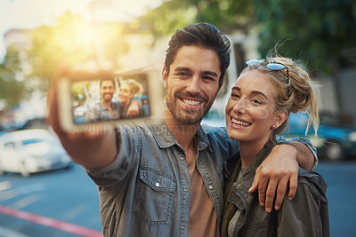 Buy stock photo Shot of a young couple taking a selfie in the city