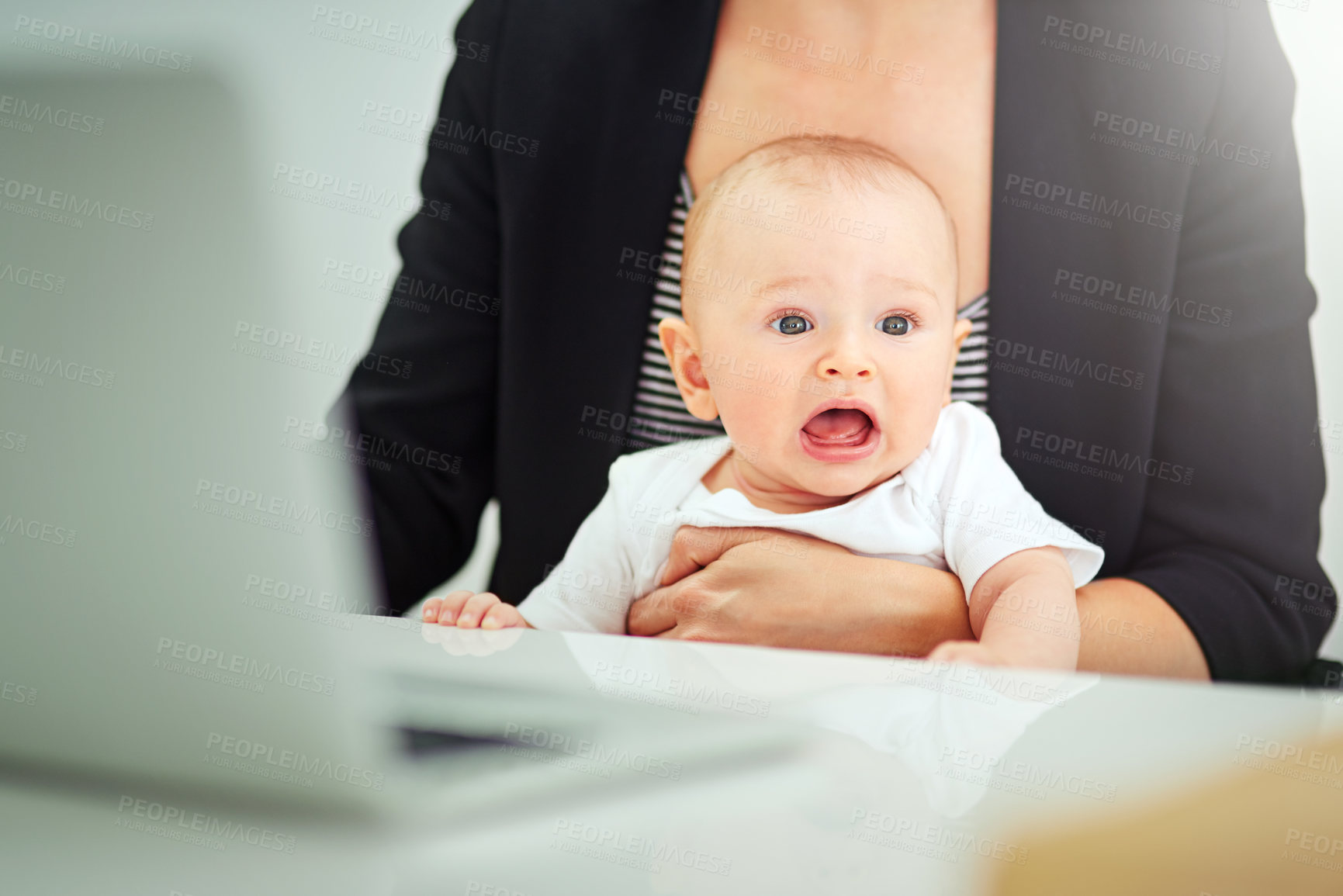 Buy stock photo Cropped shot of a businesswoman looking after her baby boy while working on her laptop