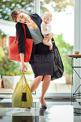 Buy stock photo Shot of a busy businesswoman carrying groceries and her baby while talking on the phone on her return from work