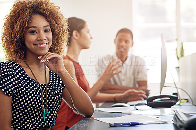 Buy stock photo Portrait of a smiling young designer sitting in an office with colleagues in the background