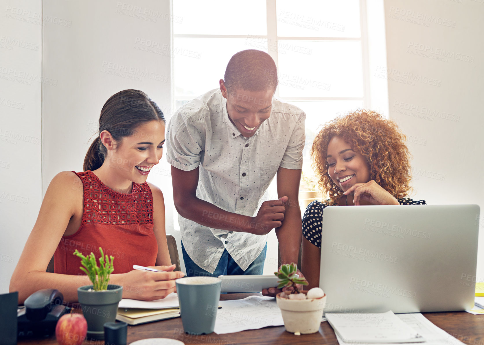 Buy stock photo Shot of a group of colleagues working together on a laptop in an office