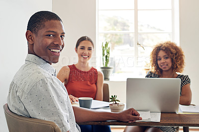Buy stock photo Portrait of a smiling young designer sitting in an office with colleagues in the background