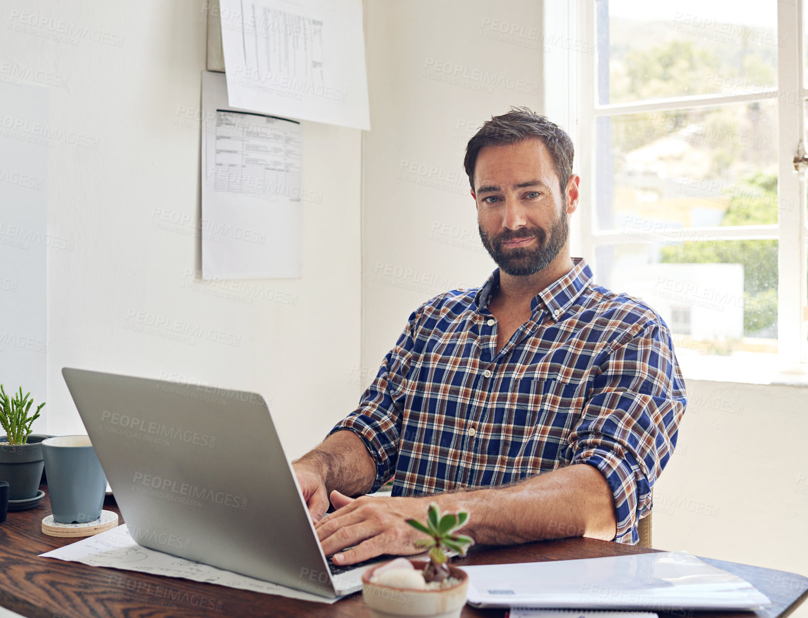 Buy stock photo Portrait of a man sitting at a desk working on a laptop